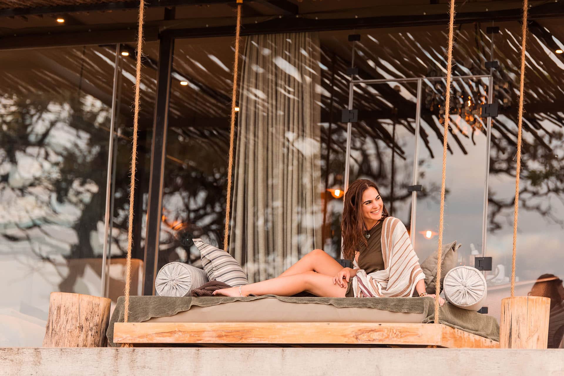 a woman smiling on an balcony hanging swing
