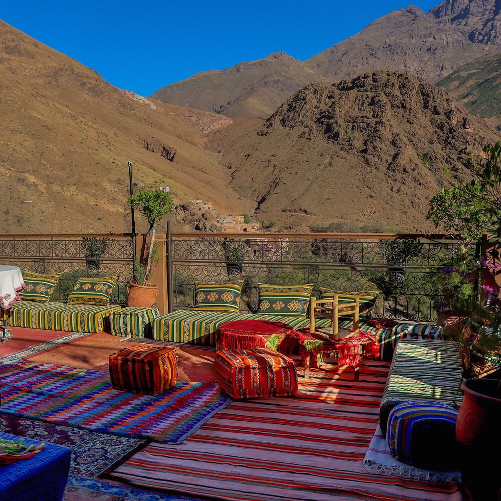 Open terrace with comfortable sofas and decorative elements in Moroccan style. The mountain landscape in the background creates an atmosphere of coziness, Eastern elegance, and outdoor relaxation.