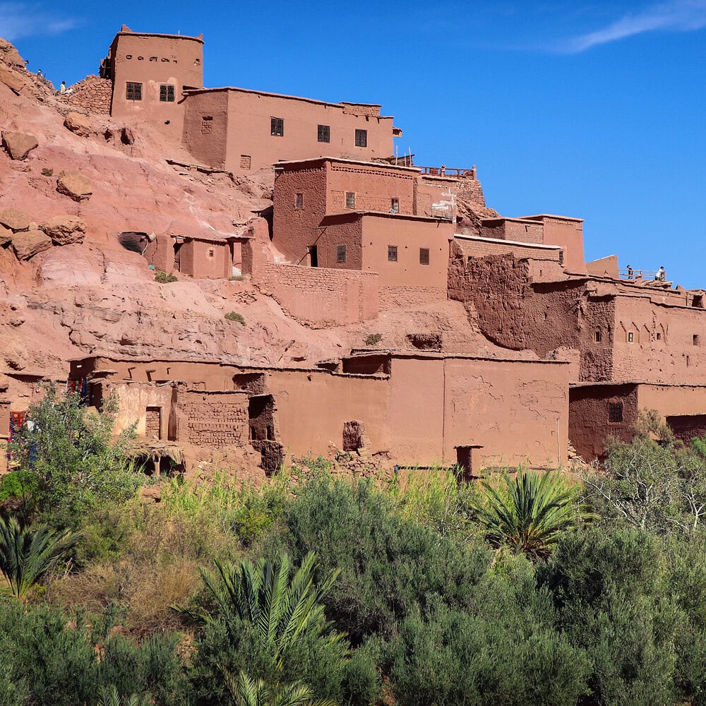 Traditional Moroccan village with clay houses and palm trees in the background. Authentic rural landscape of North Africa with distinctive architecture and natural surroundings.
